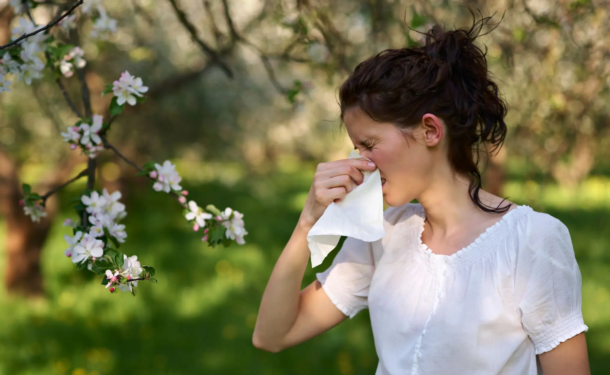 woman with tissue sneezing outside